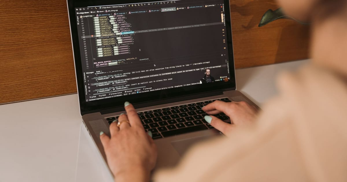 Close-up of a woman coding using a laptop in an office environment, showcasing modern technology.