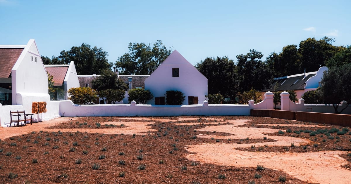 White house with a garden landscape under clear blue sky, offering a serene outdoor view.