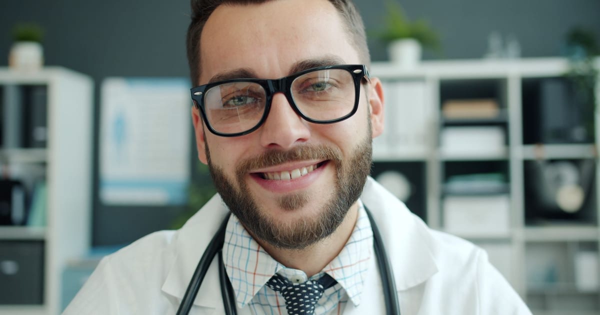 Friendly male doctor with glasses smiling in his office, promoting a professional atmosphere.