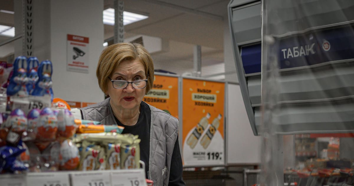 Supermarket scene with cashier and assortment of products at checkout counter.
