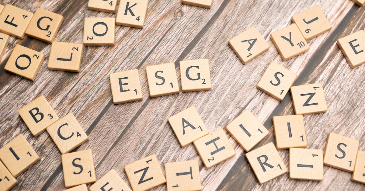 Wooden letter tiles spell ESG on a rustic wooden surface, emphasizing sustainability.
