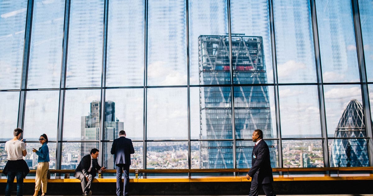 Business professionals in a modern office against a London skyline view.