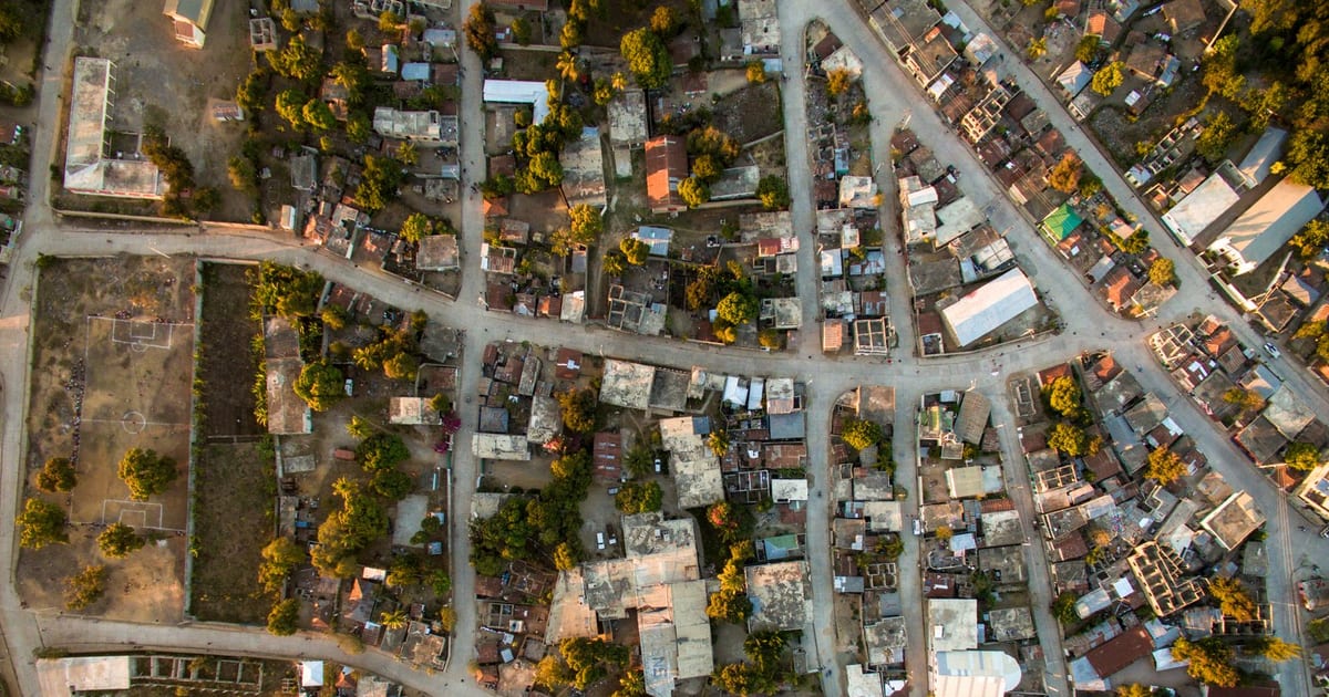 A high-angle aerial view of a bustling urban neighborhood in Haiti, showcasing roads and buildings.