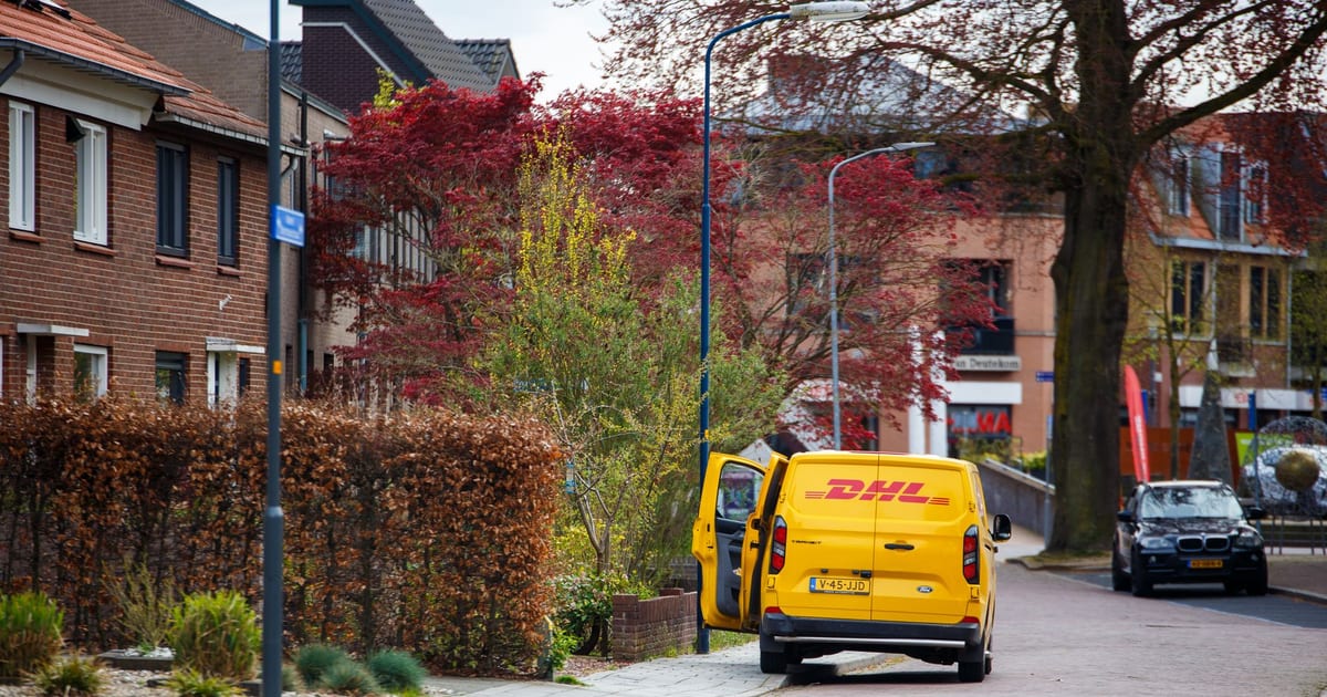 Yellow DHL van parked on a cobbled street in a suburban area with spring foliage.