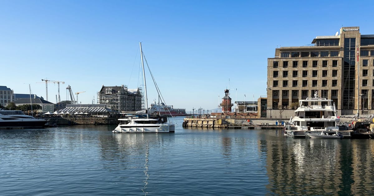 A picturesque view of a marina in Cape Town with boats and modern architecture under clear blue skies.