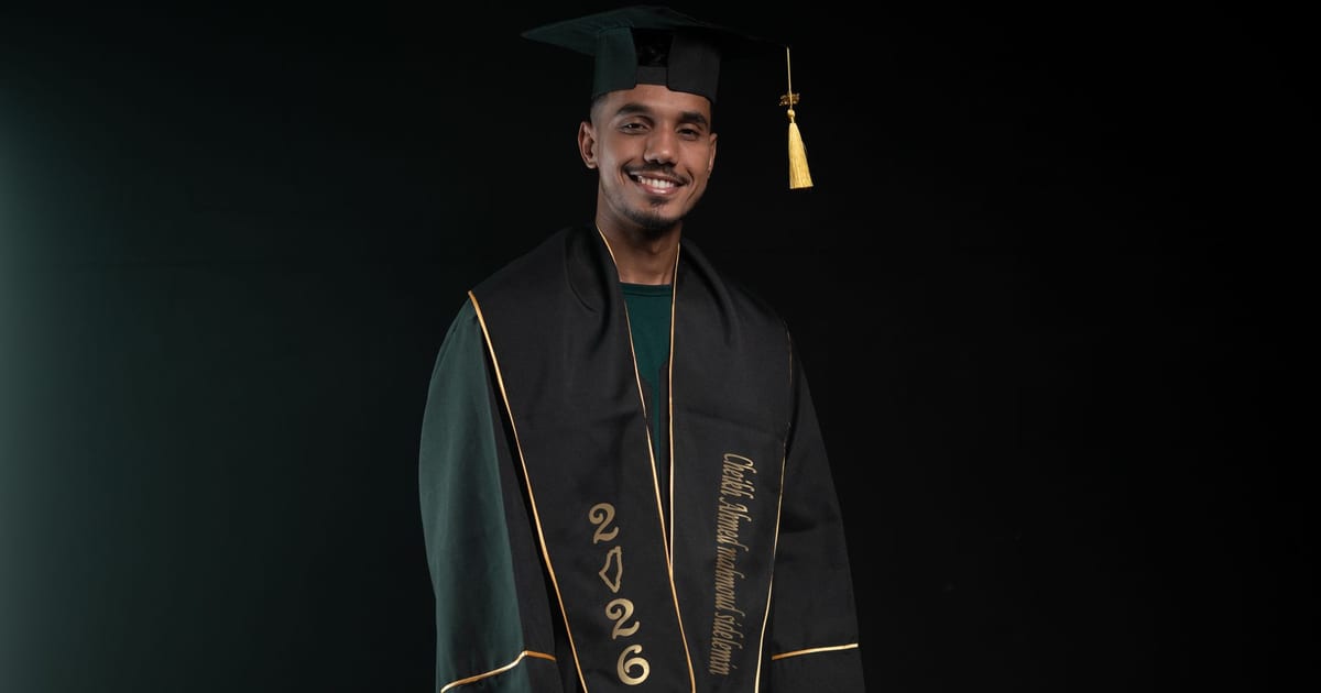 Portrait of a young male graduate smiling in cap and gown with class of 2026 inscription.