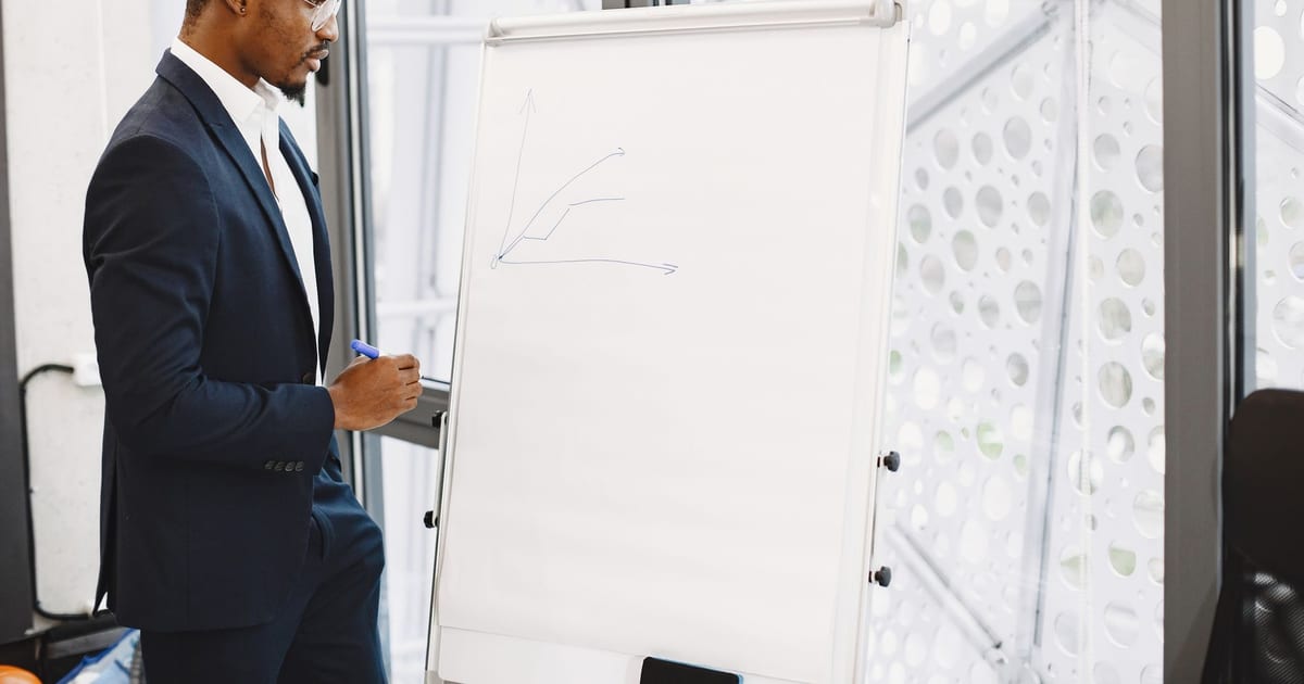 Confident businessman in a suit giving a presentation on growth strategy with a chart on a flipchart.