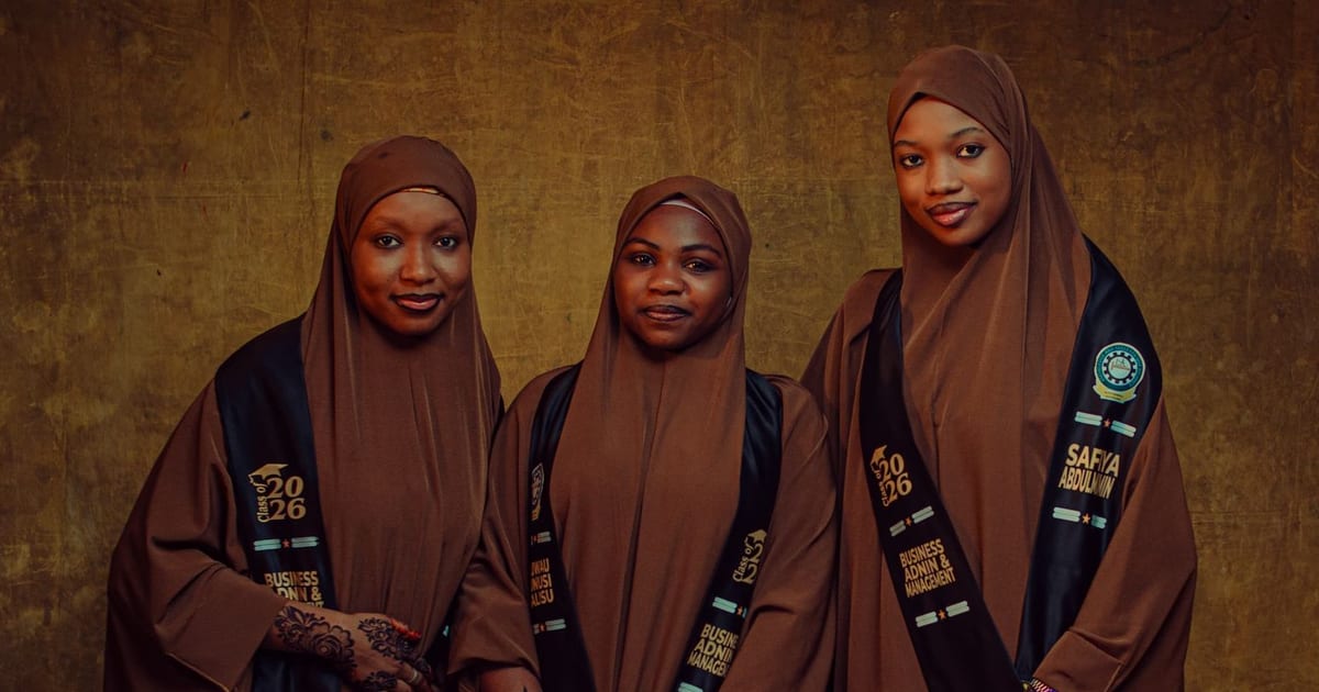 Three women in brown hijabs with henna designs wearing graduation sashes