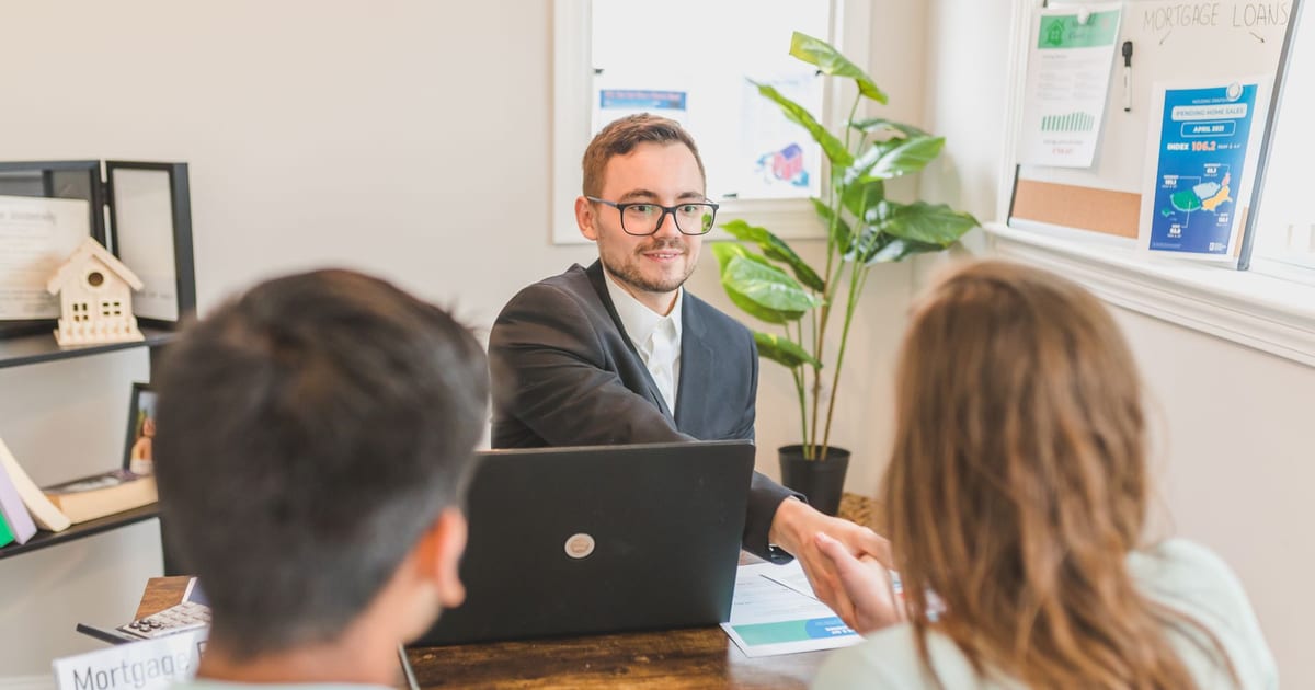 A mortgage broker meeting clients in an office, discussing agreements and loans.