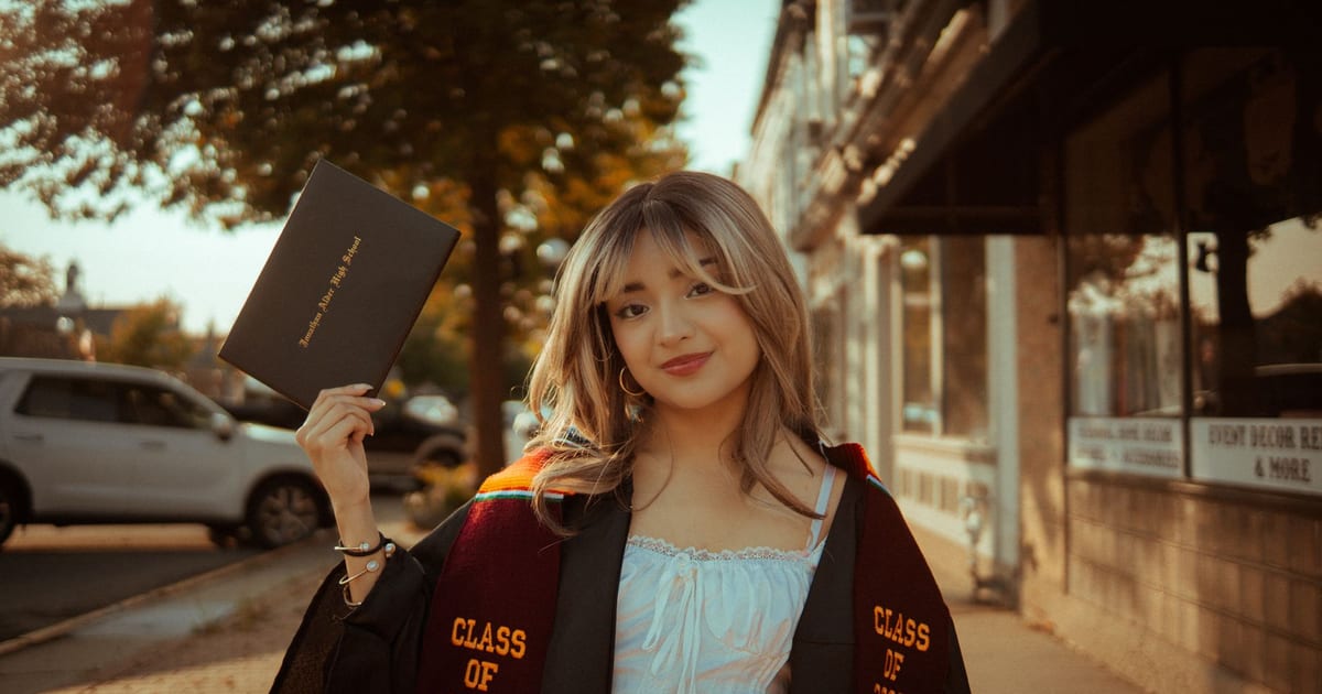 Young woman in graduation attire holding diploma, Class of 2025.