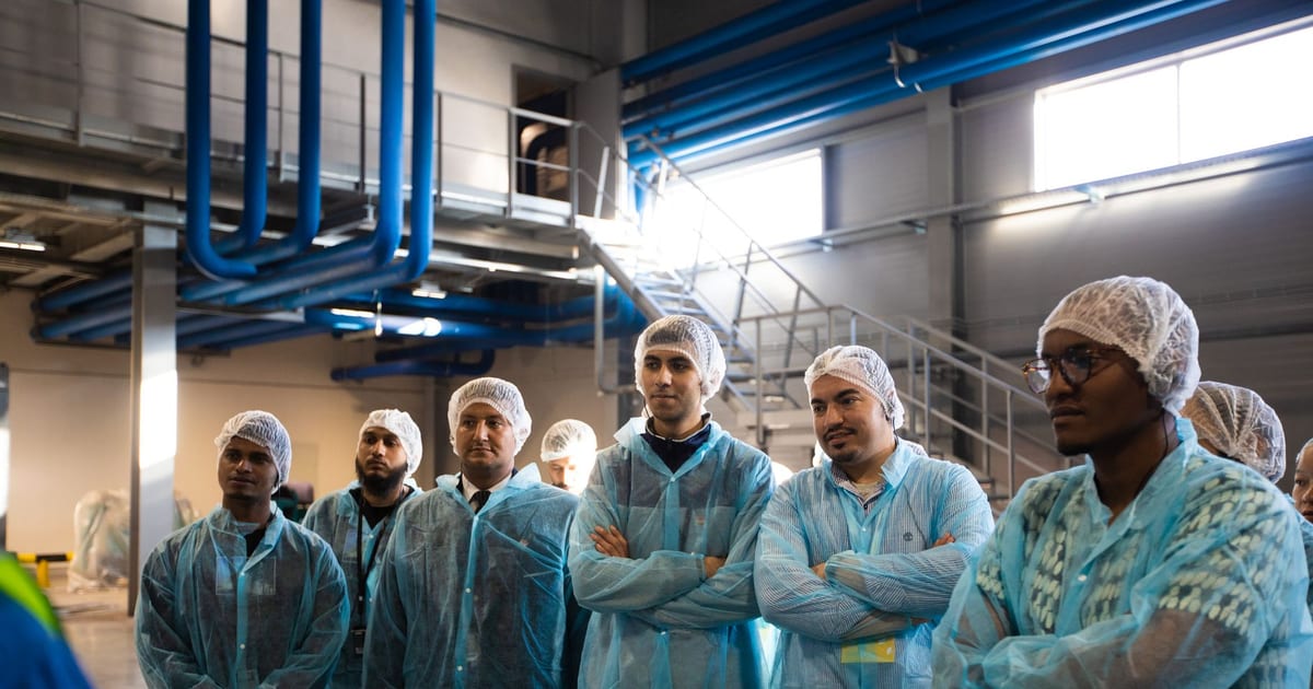 Group of diverse workers wearing blue protective clothing in an industrial setting.