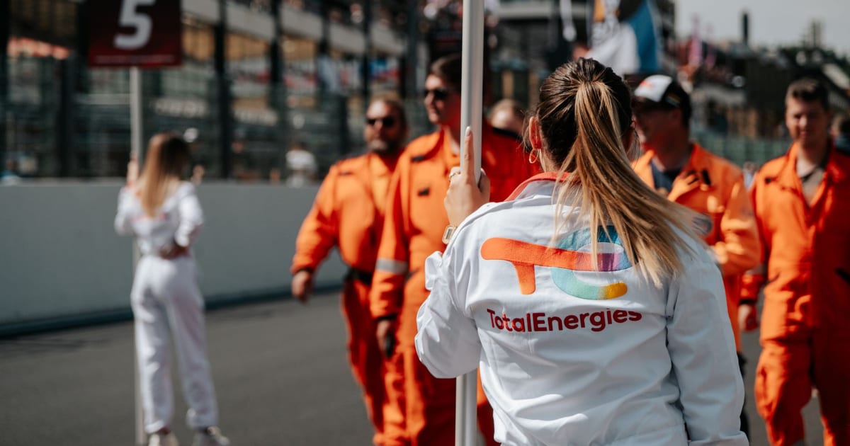 Motorsport event featuring team members and pit crew in bright uniforms at the track.