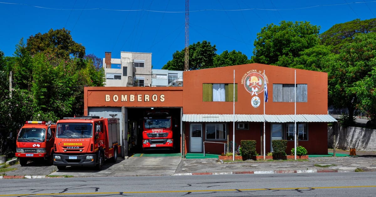 Front view of Colonia del Sacramento fire station with fire trucks parked outside.